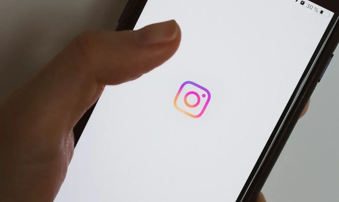 Hand holding a smartphone showing the Instagram logo on screen