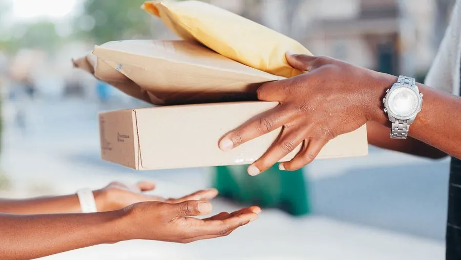 Courier handing packed online orders to a customer at the door