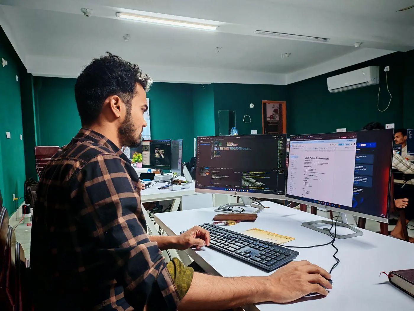 Web development Singapore team writing code for a client build on dual monitors
