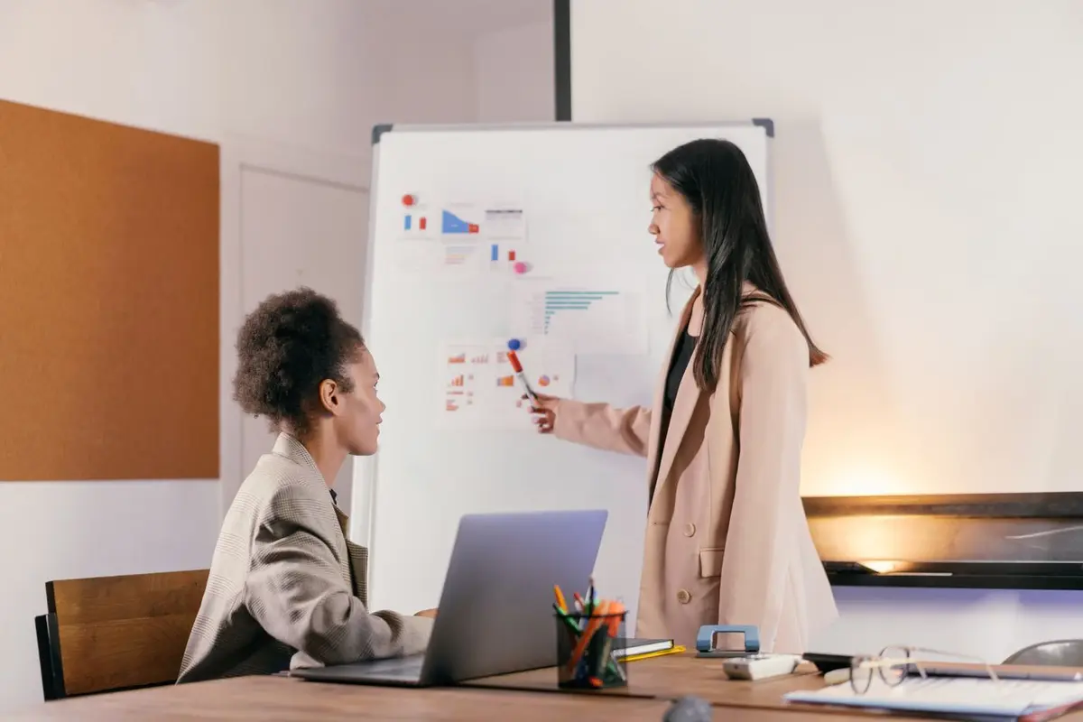 Two colleagues going through performance charts on a whiteboard together