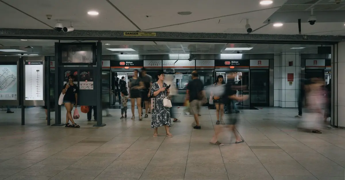Commuters crossing the Bishan MRT concourse past the platform doors marked NS 17 Bishan, with the North-South line map on the wall — station and estate names are how google maps ranking singapore searches get typed.