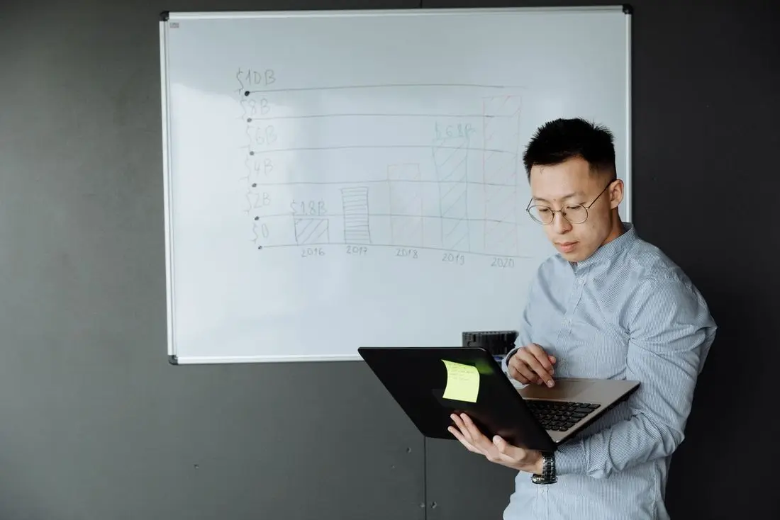 A specialist checking a laptop against a diagram drawn on a whiteboard