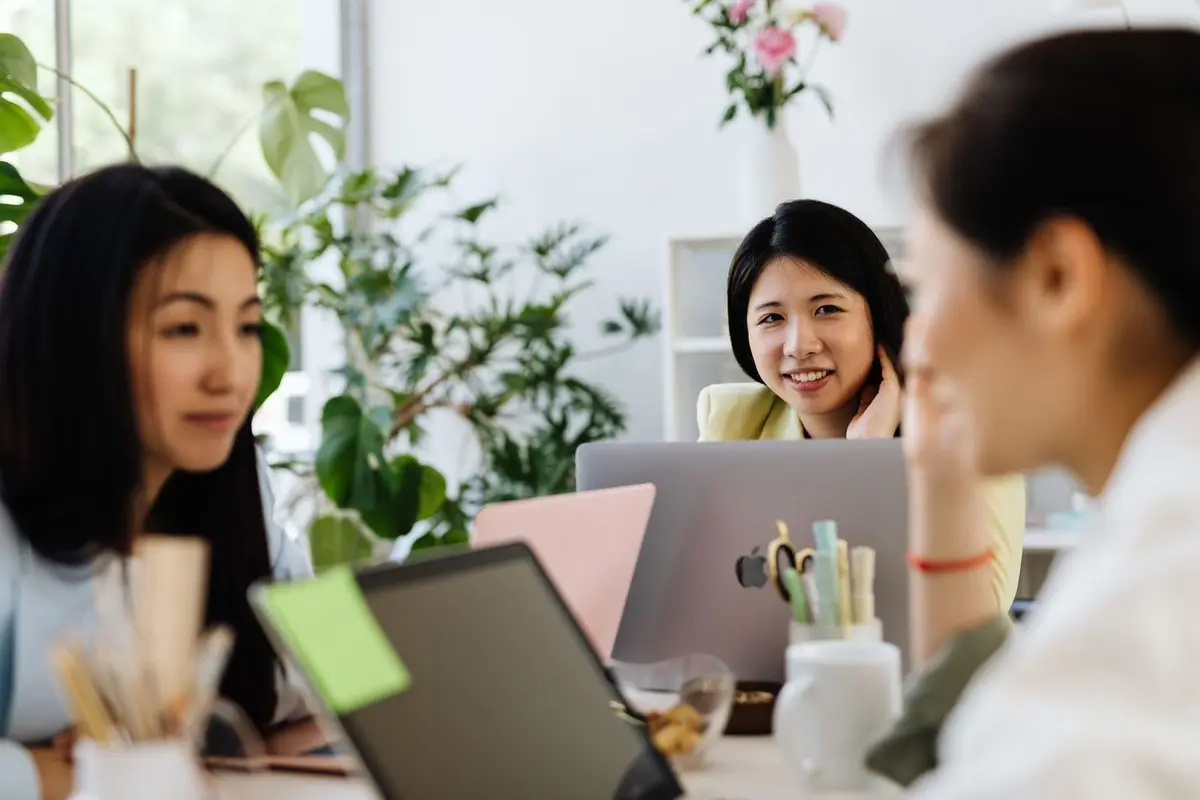 Colleagues talking over laptops in a bright Singapore office